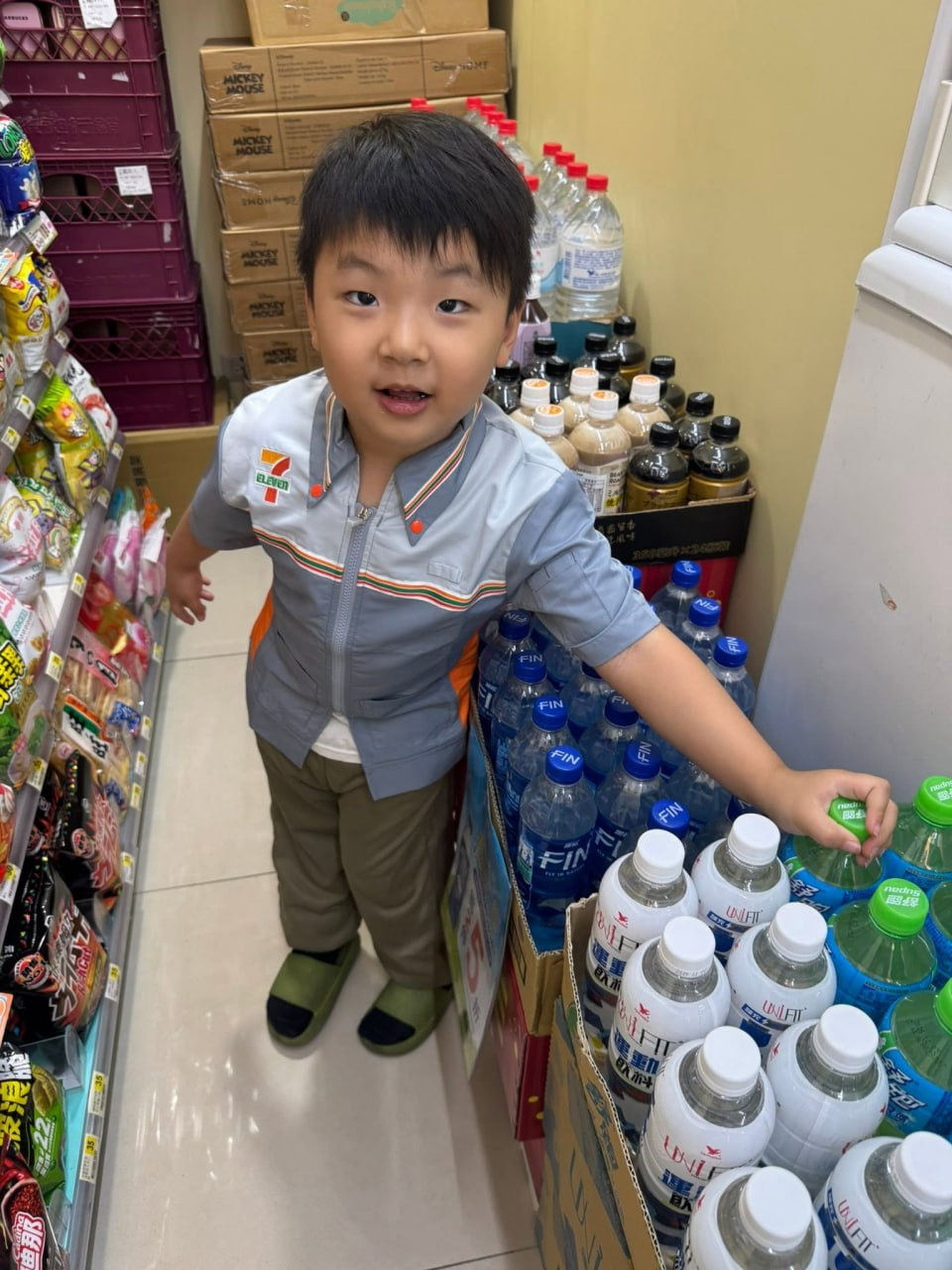 小小超商店員在貨架旁整理飲料商品
