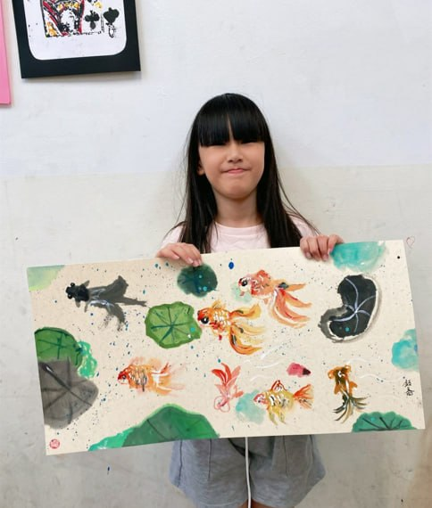 孩子展示親手完成的繽紛金魚畫作