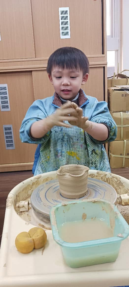 孩子雙手沾滿陶土，專注地拉出杯型