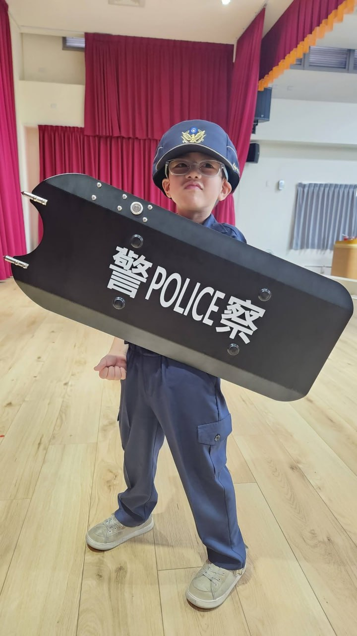 小小警察戴著警帽與墨鏡，帥氣地舉起防護盾