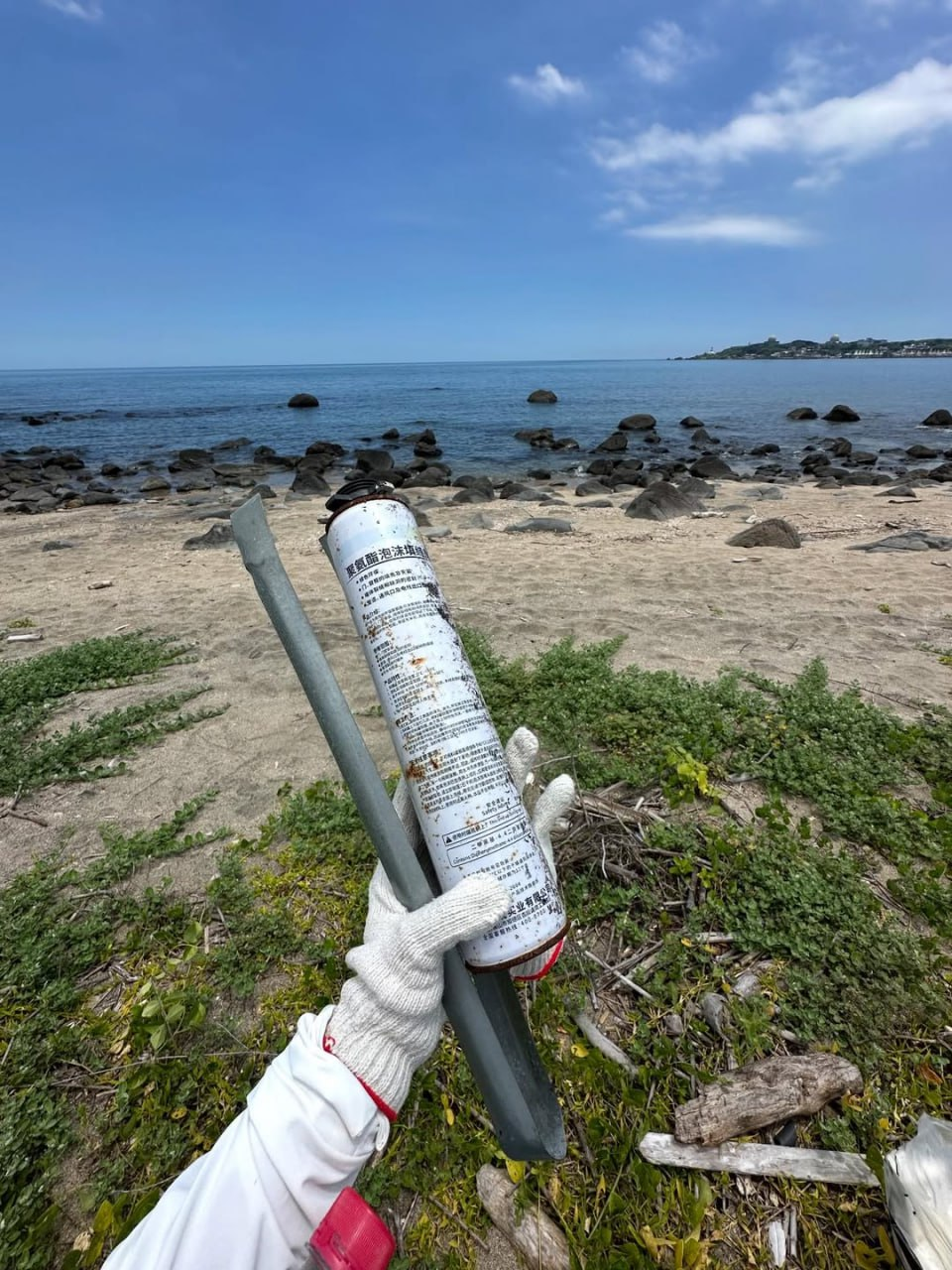 淨灘時戴著手套撿起海邊漂來的廢棄罐與鐵片