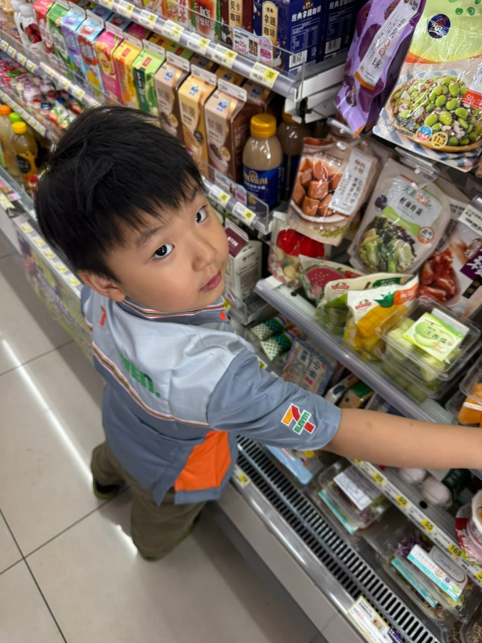 孩子伸手補貨冷藏櫃裡的商品