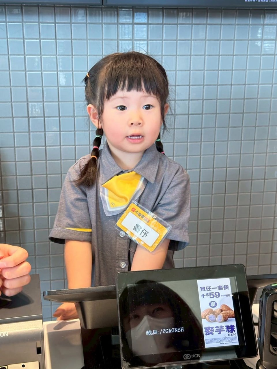 小小店員站在櫃檯前認真服務客人